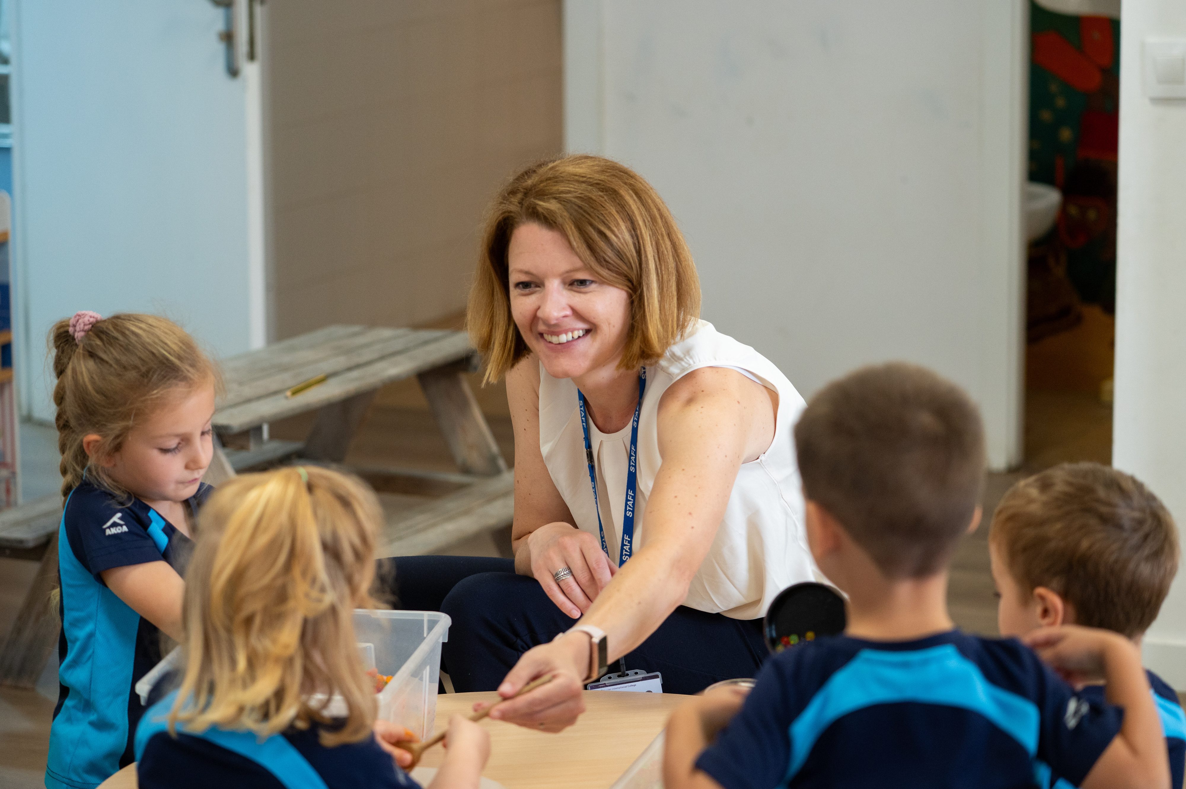 Nursery children from T3 2024-25 play with school principal Elizabeth Compton.