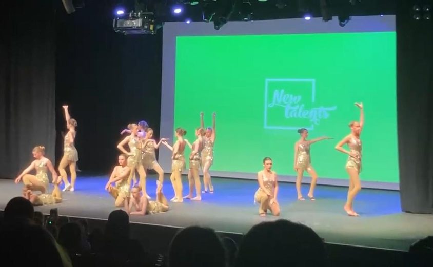 Group of dancers in gold flapper dresses performing on stage