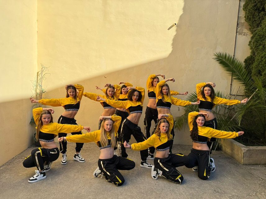 Group of dancers in yellow and black hip hop clothes posing