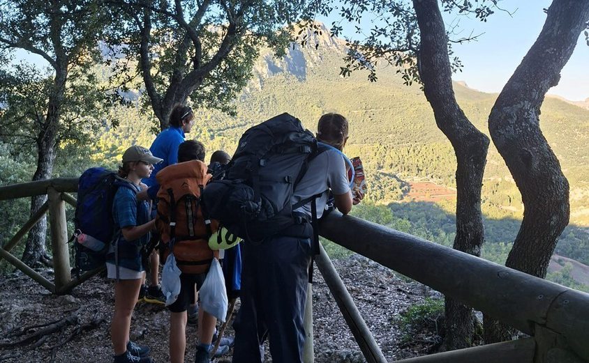 Dof E hikers with Team Lead and backpacks looking out over a fence at the view