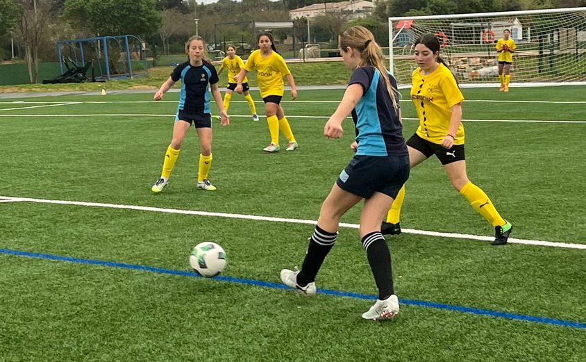 BIC girl passing to another BIC girl on the pitch in a football match against BVB