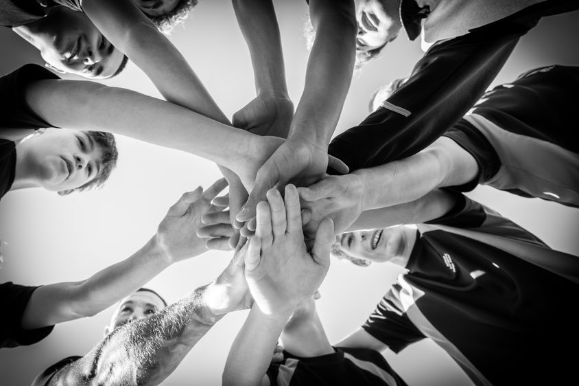 Black and white photo of Secondary boys hands in the center with the sports coach