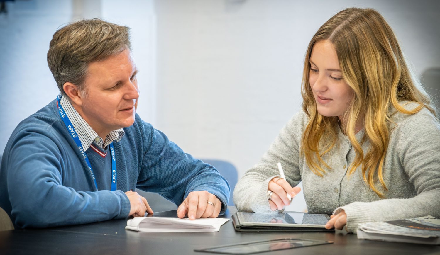 Head of Sixth form chatting with a Sixth Form girl at a table in the common room