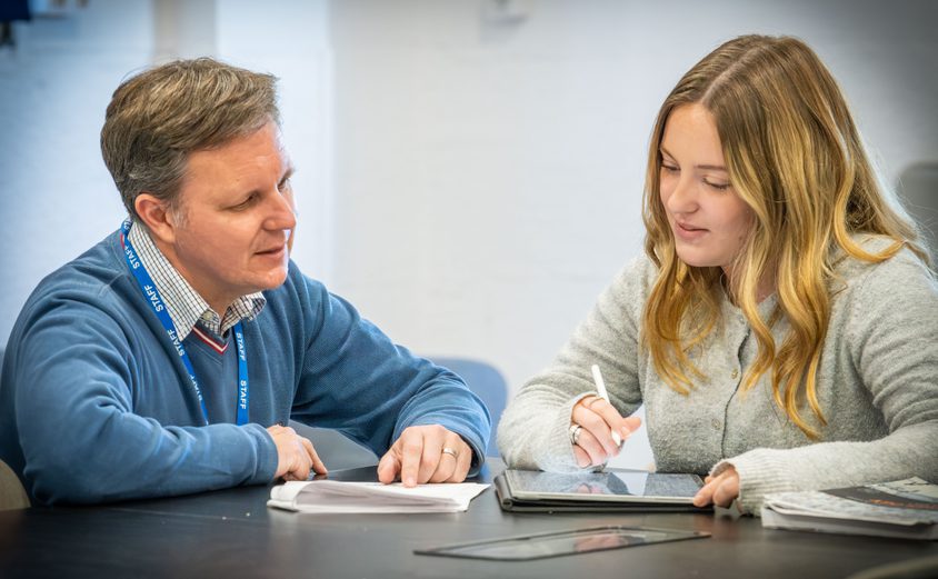 Head of Sixth form chatting with a Sixth Form girl at a table in the common room
