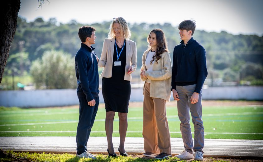 Principal chatting to three Sixth Formers in front of our football pitch