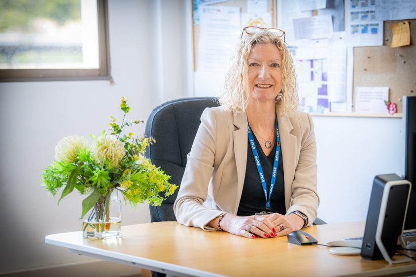 Principal sitting at her desk smiling