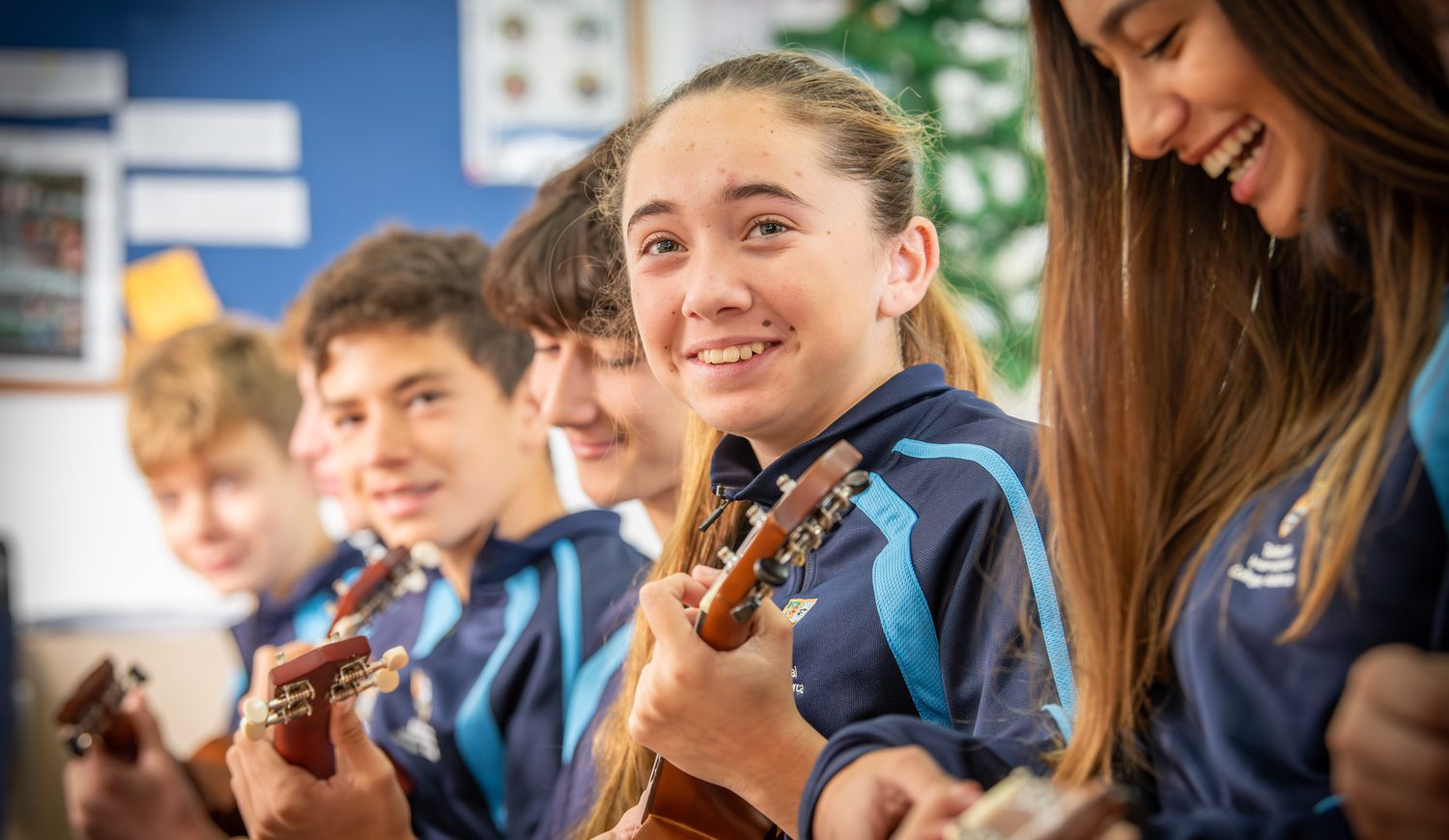 Secondary students playing the ukulele and smiling