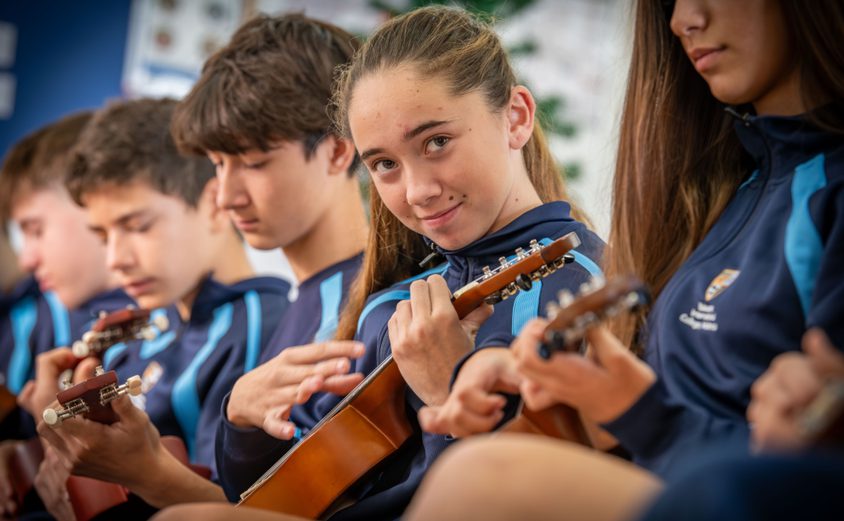 Secondary students playing ukuleles