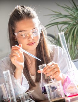 Sixth Form Girl dropping chemicals into a beaker with a dropper in school science lab