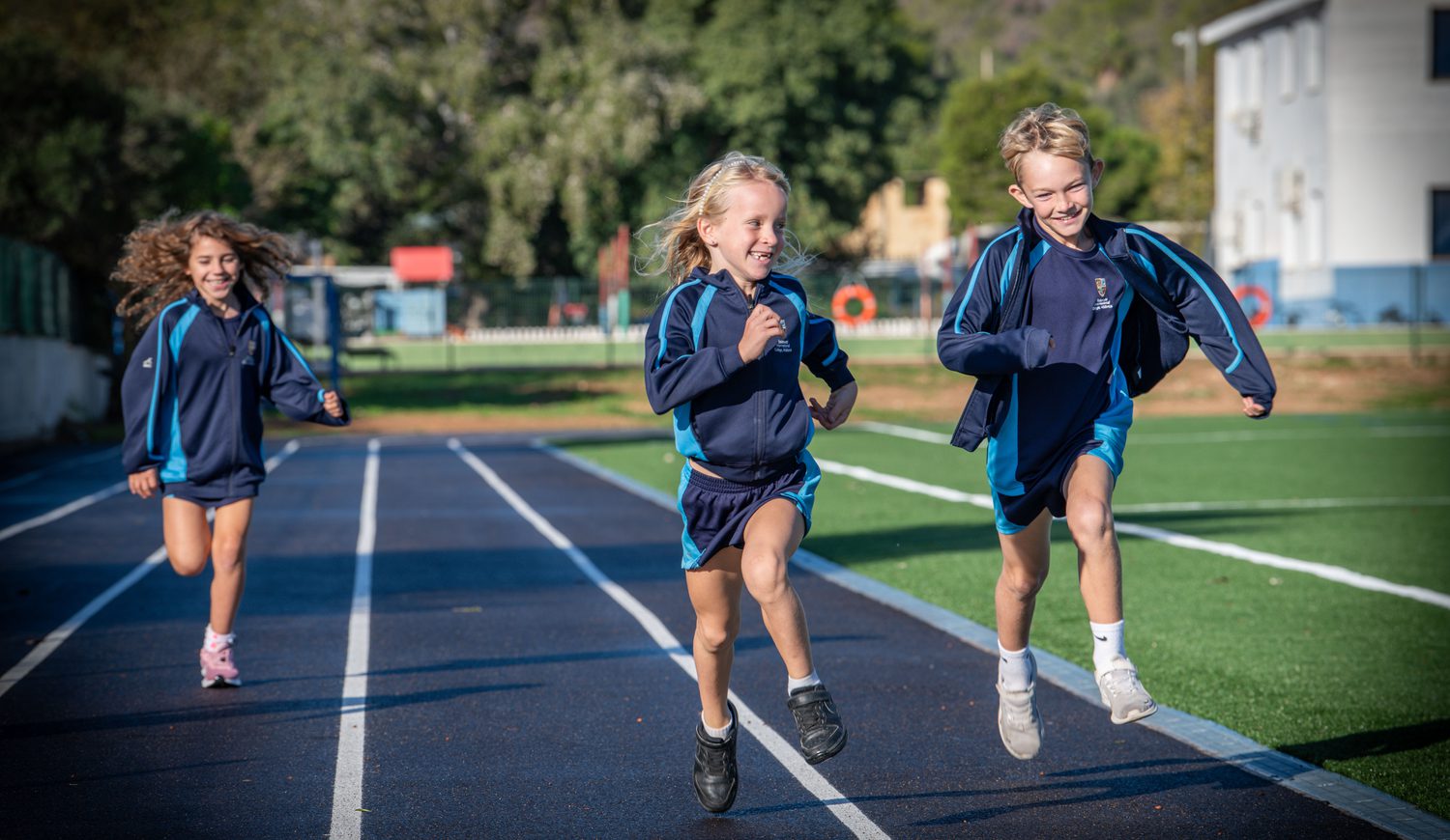 Three Primary children running on the school Astro Turf