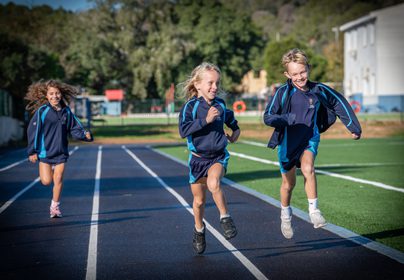 Three Primary children running on the school Astro Turf