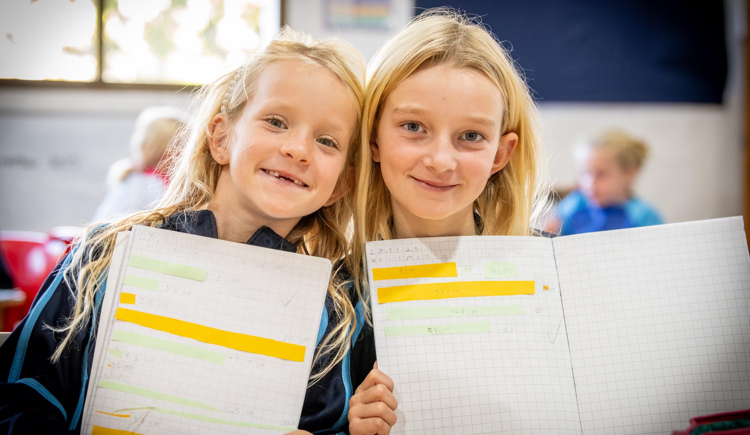 Two Year 3 students smiling and showing off their maths books
