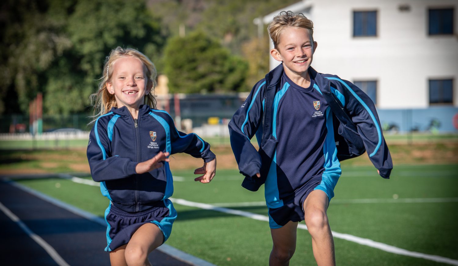 Two primary students running on the running track