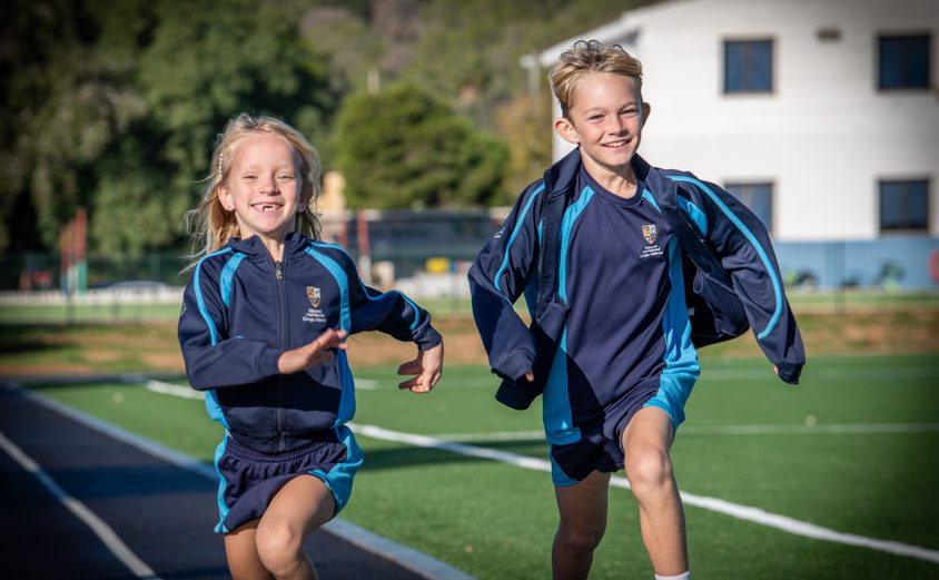 Two primary students running on the running track