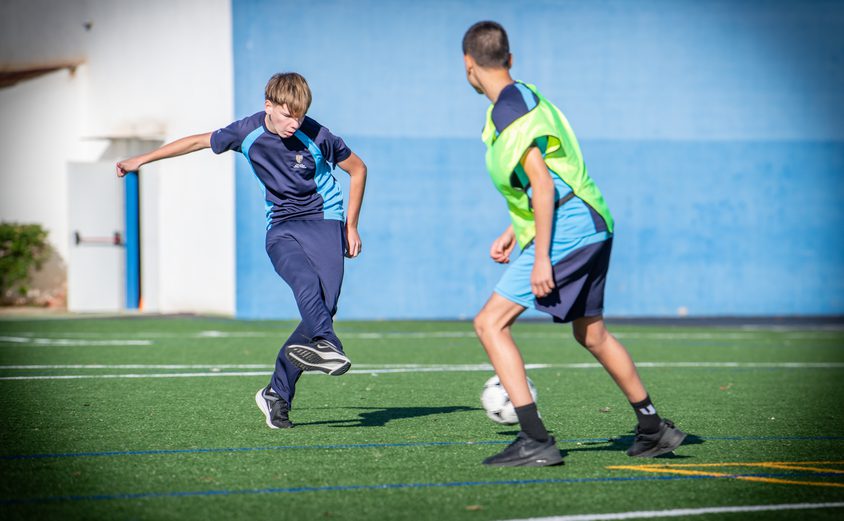 Two secondary students playing football on the Astro Turf