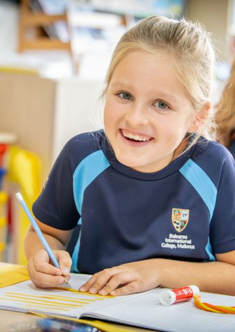 Year 3 girl working at her desk looking up and smiling