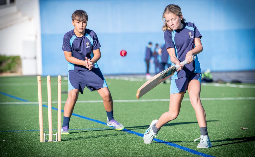 Year 7 girl batting in cricket with the wicket keeper behind on the Astro Turf